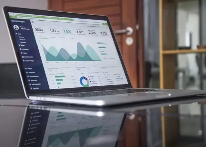 Laptop showing an analytics dashboard with charts and KPIs in green