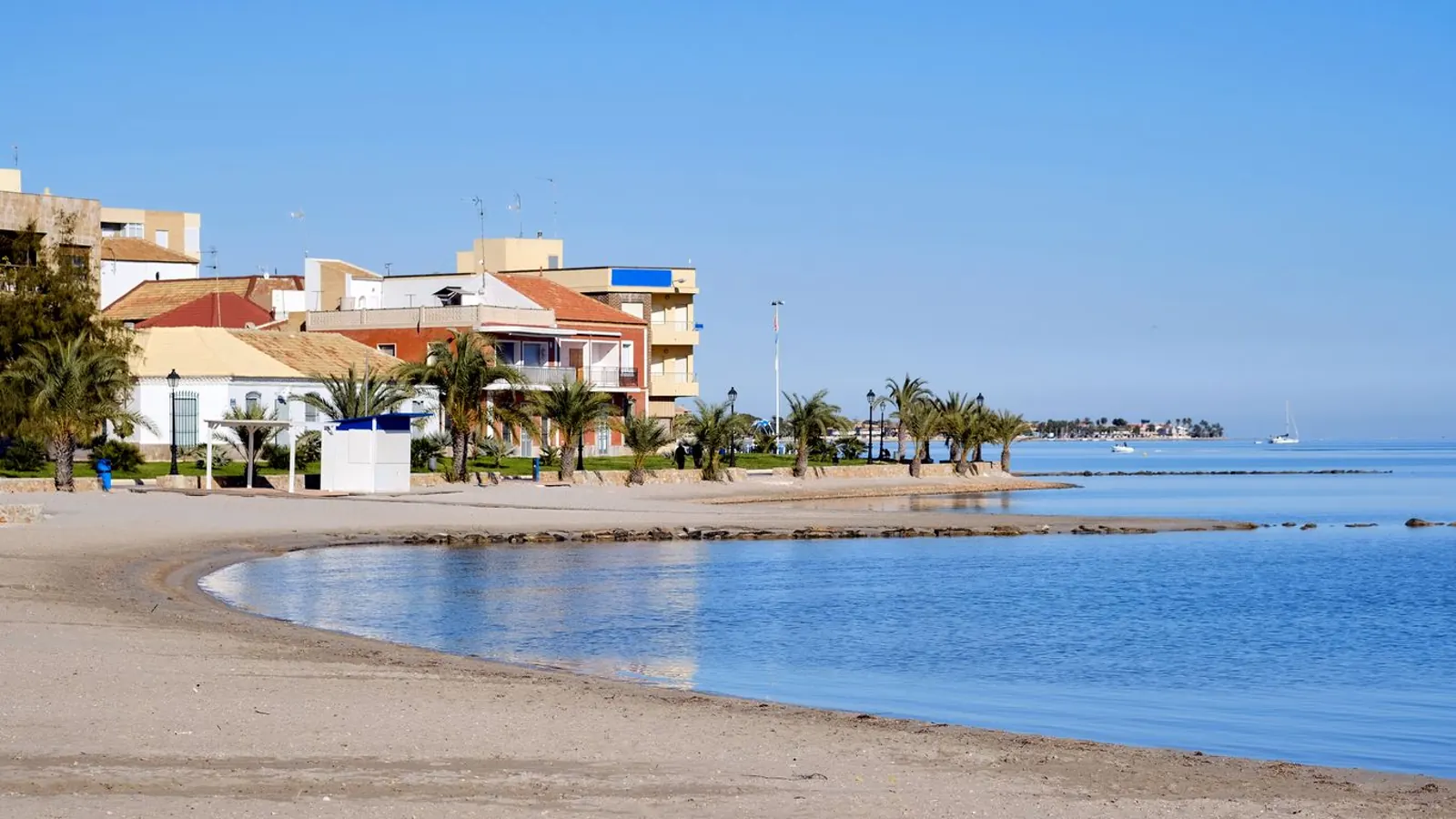 Playa urbana de arena fina con palmeras y paseo marítimo en Los Alcázares, Mar Menor