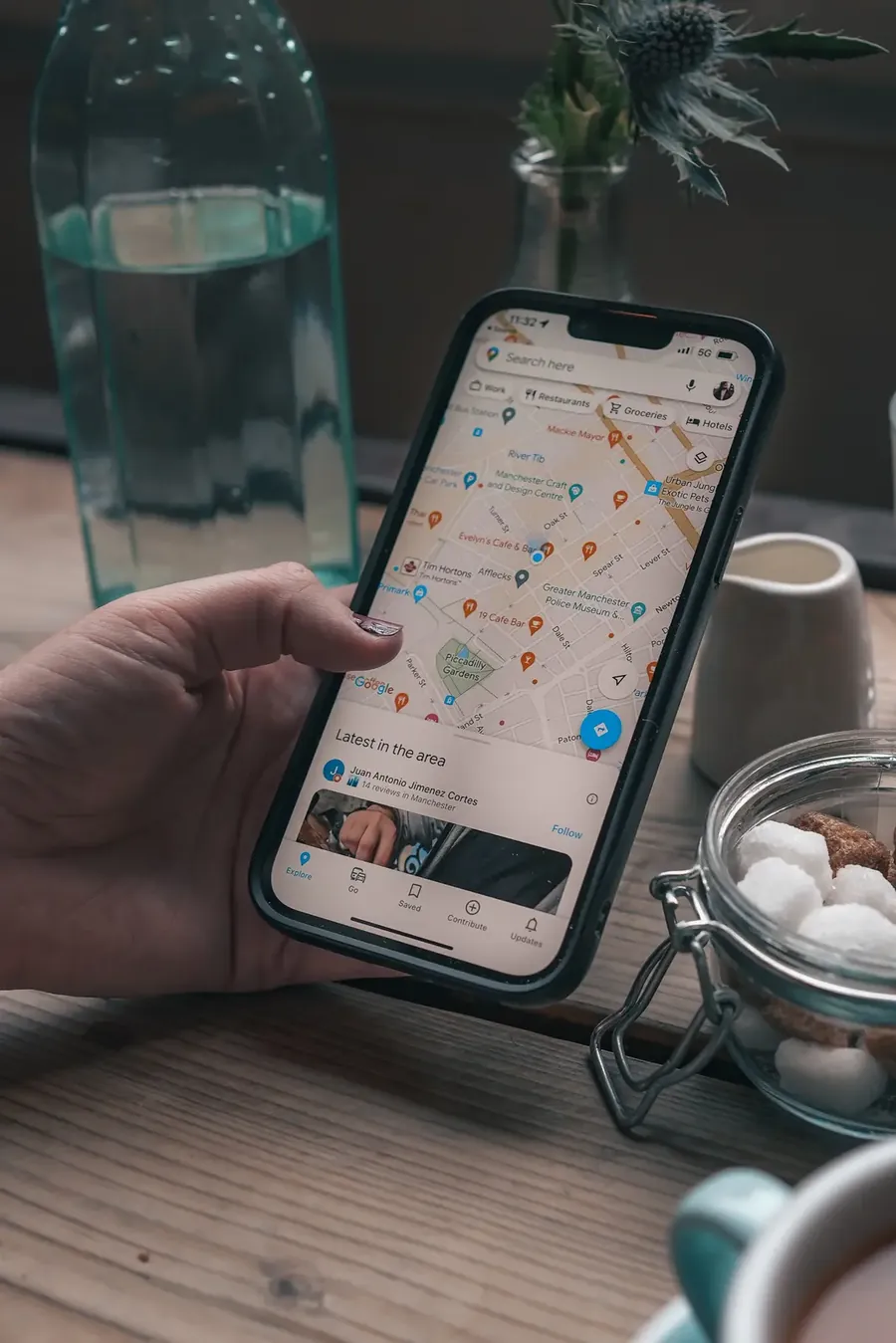 Mano sosteniendo un móvil con Google Maps abierto buscando negocios cercanos