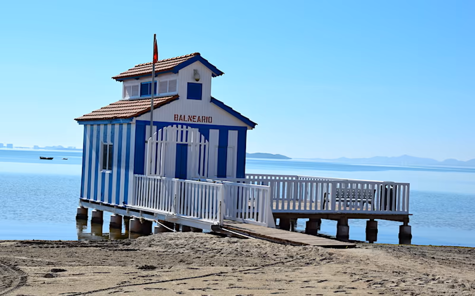 Balneario de la Encarnación de rayas azules y blancas sobre pilotes en el Mar Menor a la altura de Los Alcázares