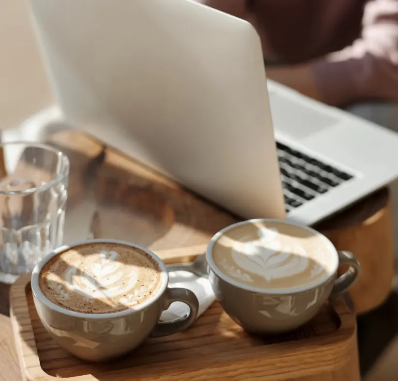 Dos cafés con arte latte junto a un portátil, reunión con cliente en San Javier
