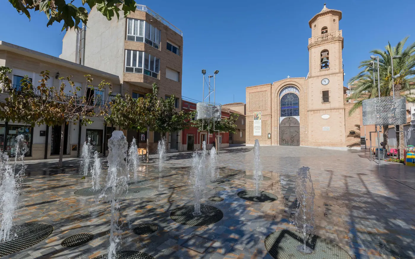 Plaza de la Iglesia Nuestra Señora del Pilar con fuentes en el casco de Pilar de la Horadada, zona donde Inteclia atiende a comercio y hostelería local