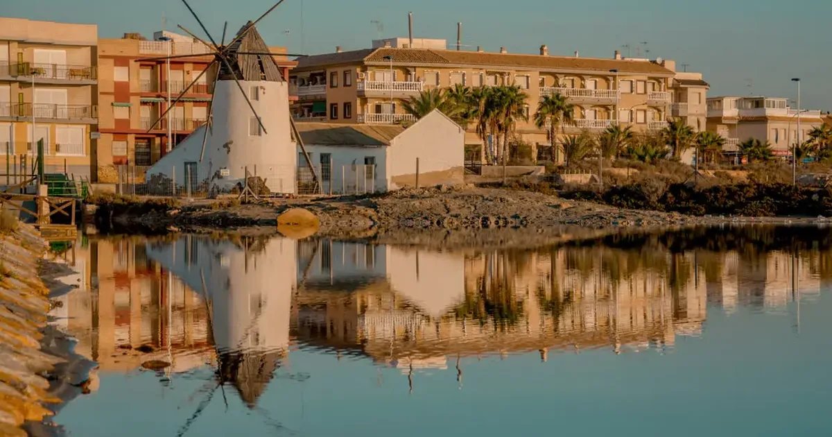 Molino y paseo marítimo reflejados en el Mar Menor al atardecer, símbolo de los negocios locales de la ribera